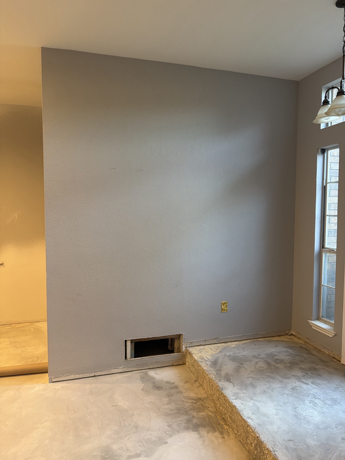 Large interior wall with low rectangular opening and adjacent window